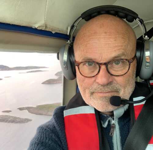 Bilde av Per Tomas Govertsen i fly med utsikt over landskap.