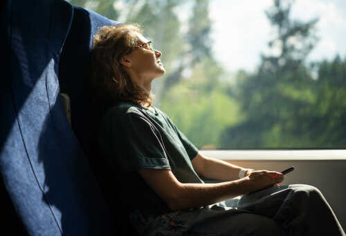 Bilde av dame som slappe av på buss og nyter turen med lukkede øyne.