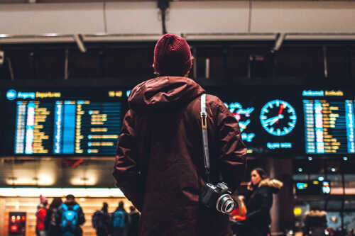 Bilde av mann som står å ser på digitaltavle på jernbanestasjon.