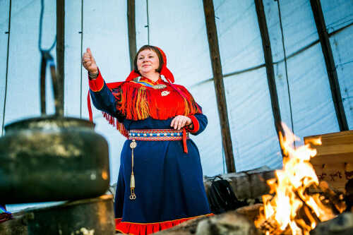 Bilde av samisk dame ved bål som forteller historie.