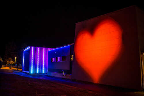 Lyssatt Nordland Teater om kvelden med forskjellige farger og rødt hjerte på veggen.